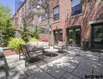 Paved rear courtyard with outdoor seating against exposed brick