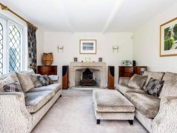 Five-Bedroom Town House on Rue de Rivoli - Sitting room with two sofas drawn up to an open fireplace beside a leaded window